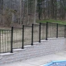 black iron fence and stone retaining wall